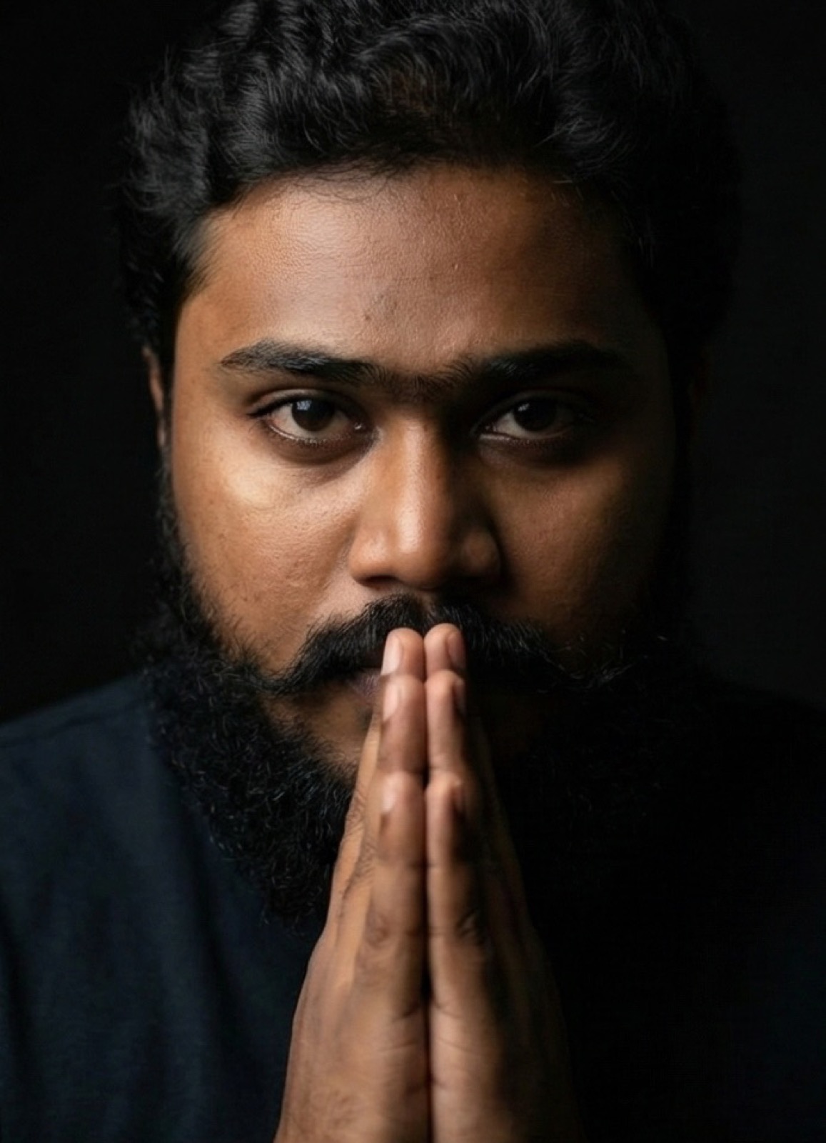 thrinadhsai author portrait in dark studio with folded hands